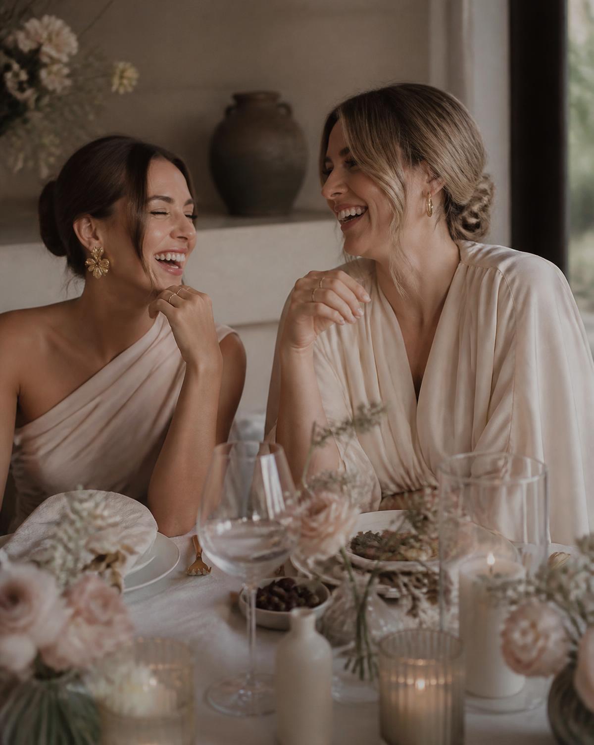 Two women laughing together at a beautifully styled table